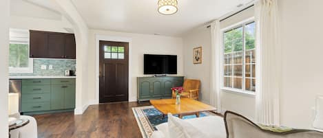 A modern living room with a wooden floor, a sofa, a coffee table, and a television.