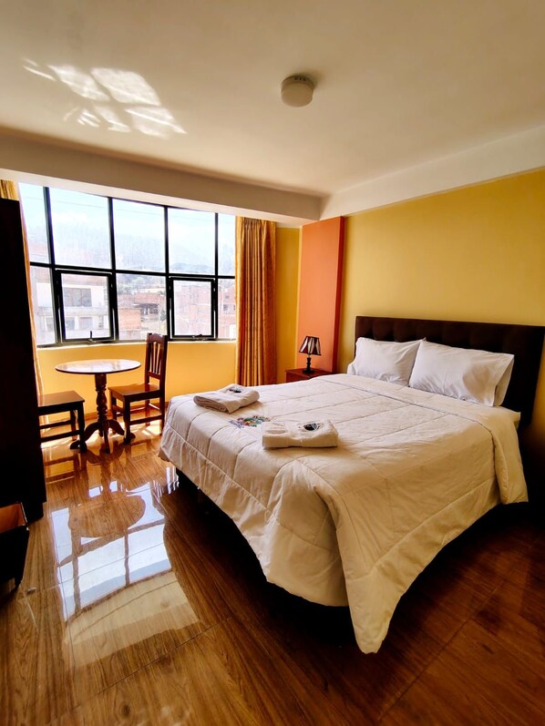 A hotel room with a bed, a table, chairs, a window, and a lamp. - HOTEL EL CASTOR HUARAZ (Huaraz)