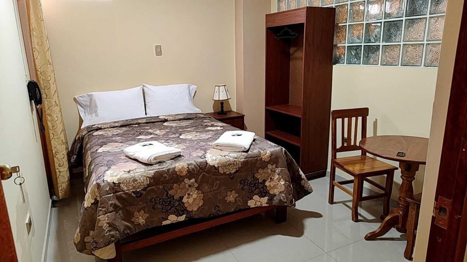 Un dormitorio con cama, mesita de noche, silla y armario.