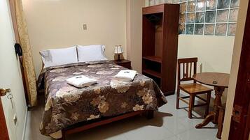 Un dormitorio con cama, mesita de noche, silla y armario.