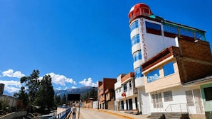 A hotel with a prominent cylindrical tower, a clear sky, and a mountain in the background.