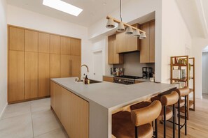 A modern kitchen with wooden cabinets, a central island with bar stools, and pendant lighting. - Topanga Canyon Oasis - 3 Homes & Pool - C&C | 12 (Topanga)