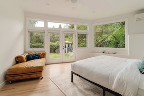 A bedroom with a bed, a sofa, and a view of a garden through large windows. - Topanga Canyon Oasis - 3 Homes & Pool - C&C | 12 (Topanga)