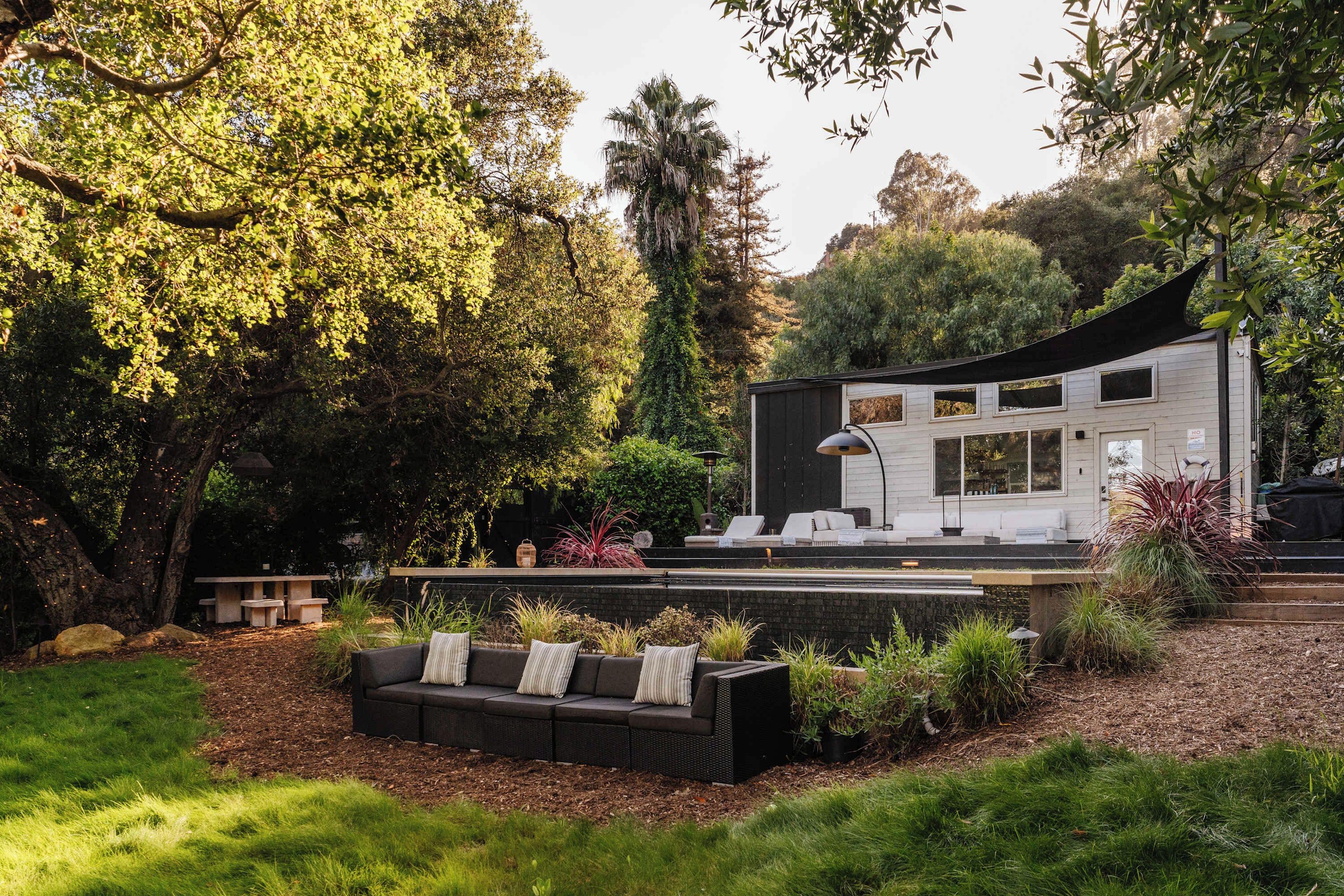 Una casa moderna con un patio, mobiliario exterior y un jardín.