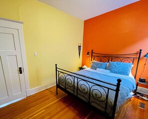 Ein Schlafzimmer mit einem Bett, einer Tür und einer Wand mit Lichtschalter.