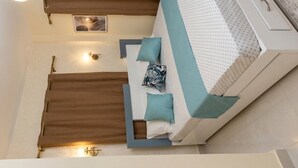 Ein Bett mit weiß-blauer Kopfteil, zwei Kissen und einem braunen Vorhang.