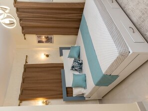 Un lit avec une tête de lit blanche et bleue, deux oreillers et un rideau marron.