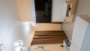 Ein Zimmer mit einem Bett, einem kleinen Tisch, einem Stuhl, einem Spiegel und einem Fenster.