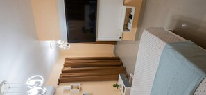 Une pièce comprenant un lit, une petite table, une chaise, un miroir et une fenêtre.