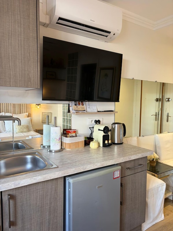 Et moderne køkken med opvaskemaskine, fladskærms-TV og kaffemaskine.