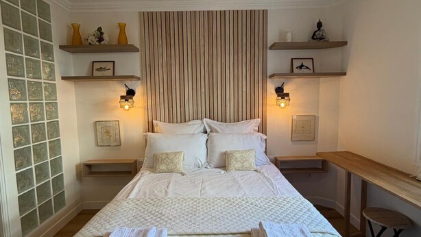 Ein Schlafzimmer mit einem großen Bett, Nachttischen, einem Holzkopfteil, Wandregalen und einem Deckenventilator.