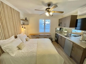 A bedroom with a bed, a ceiling fan, a window, and a kitchenette with a microwave and sink. - La Croisette - Plage - Clim - Calme (Cannes)