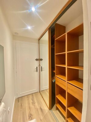 Ein Zimmer mit Holzboden, einer weißen Tür und einer eingebauten Holzregaleinheit.