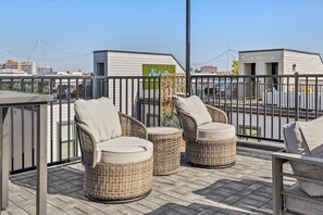A rooftop terrace with wicker furniture and a view of the cityscape. - Lux Home Close to Broadway • Rooftop Views & FirePit! (Nashville)