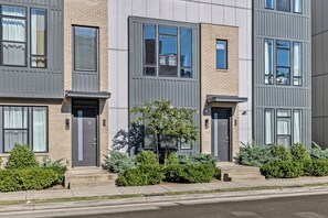 A row of modern townhouses with grey siding, large windows, and a small tree in the center. - Lux Home Close to Broadway • Rooftop Views & FirePit! (Nashville)