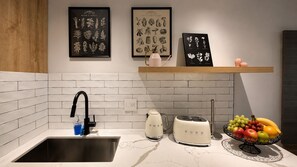 Eine Küche mit Spüle, Wasserkocher, Toaster und Obstschale. An der Wand befinden sich gerahmte botanische Drucke.