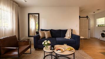 A living room with a sofa, coffee table, and a washing machine in the background.