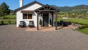 Einbungalow mit überdachter Veranda, Schornstein und Auffahrt mit Kies.