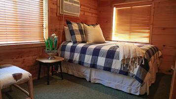 A cozy bedroom with a bed, a small table, and a chair.