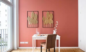 A room with a white desk, a brown chair, and two framed wall decorations. - AN EXCELLENT COMBINATION OF MODERN AMENITIES, GENEROUS LIVING SPACE IN THE HEART (Berlin)
