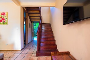 Eine Holztreppe führt zu einer Zwischenebene, an der ein Flachbildfernseher an der Wand befestigt ist.