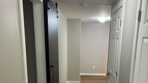 Un corridoio con una porta scorrevole, pavimento in legno e pareti bianche.