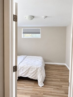 A bedroom with a bed, a window, and a ceiling light fixture. - Private Basement living Suite | Living Room near Casino Moncton NB (Moncton)