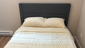 Un letto con una testiera scura e un piumone color crema.