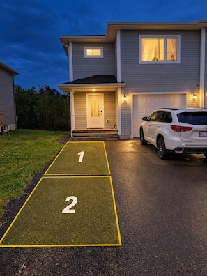 A two-story house with a driveway leading to a garage. - Private Basement living Suite | Living Room near Casino Moncton NB (Moncton)