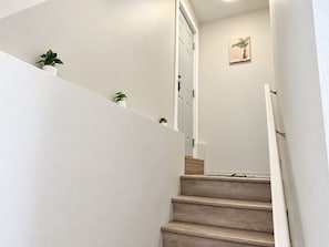 Eine Treppe mit Handlauf, eine Tür am oberen Ende und ein kleiner Blumentopf auf der Zwischenebene.