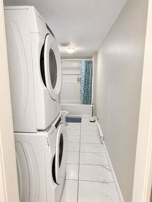 A laundry room with stacked washing machines and a shower area. - Private Basement living Suite | Living Room near Casino Moncton NB (Moncton)