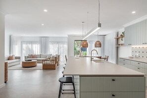 Une cuisine moderne dotée d’un îlot central, de meubles de couleur claire et d’un éclairage suspendu.