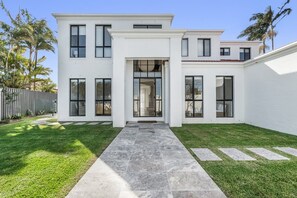 Um edifício moderno de dois andares com entrada central, janelas amplas e um gramado bem cuidado.