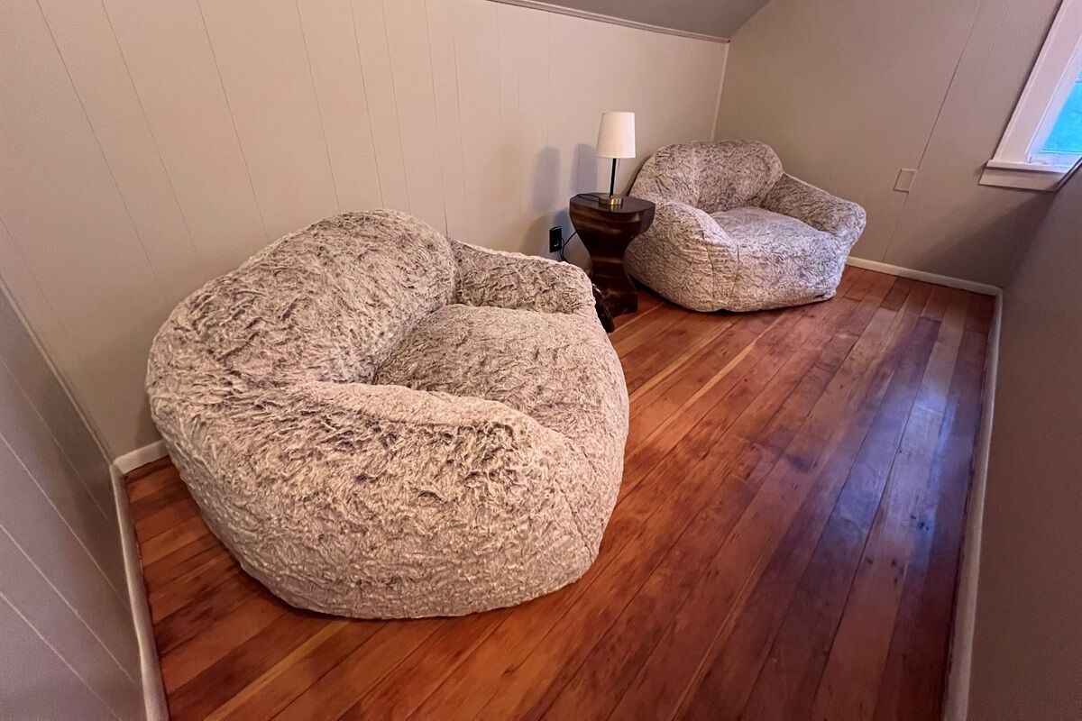 Una habitación con un sillón grande y texturizado tipo bean bag y otro más pequeño similar, ambos sobre piso de madera.