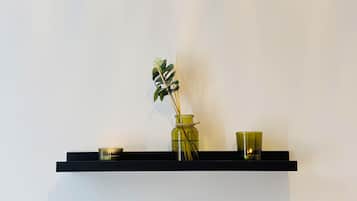 Una repisa con una botella de vidrio verde, un cuenco pequeño y una taza de vidrio verde.