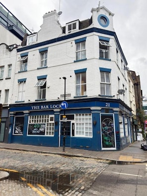Un edificio con fachada azul y blanca, un letrero que dice 'The Bar Lock' y el número '21' en la esquina.
