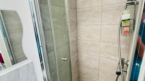 A bathroom with a glass-enclosed shower, a white sink, and a tiled wall. - Hotel Haven London, near Tower Bridge (London)