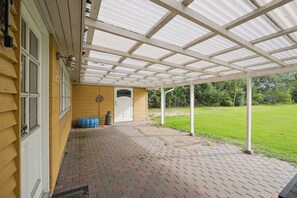 A covered patio area with a brick floor and a white door. - Holiday home with large garden by Limfjord (Storvorde)