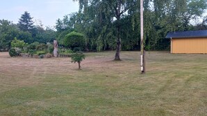 A grassy outdoor area with trees and a wooden shed. - Holiday home with large garden by Limfjord (Storvorde)