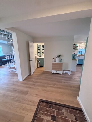 A spacious living area with a staircase, a kitchen, and a bathroom visible through an open door.