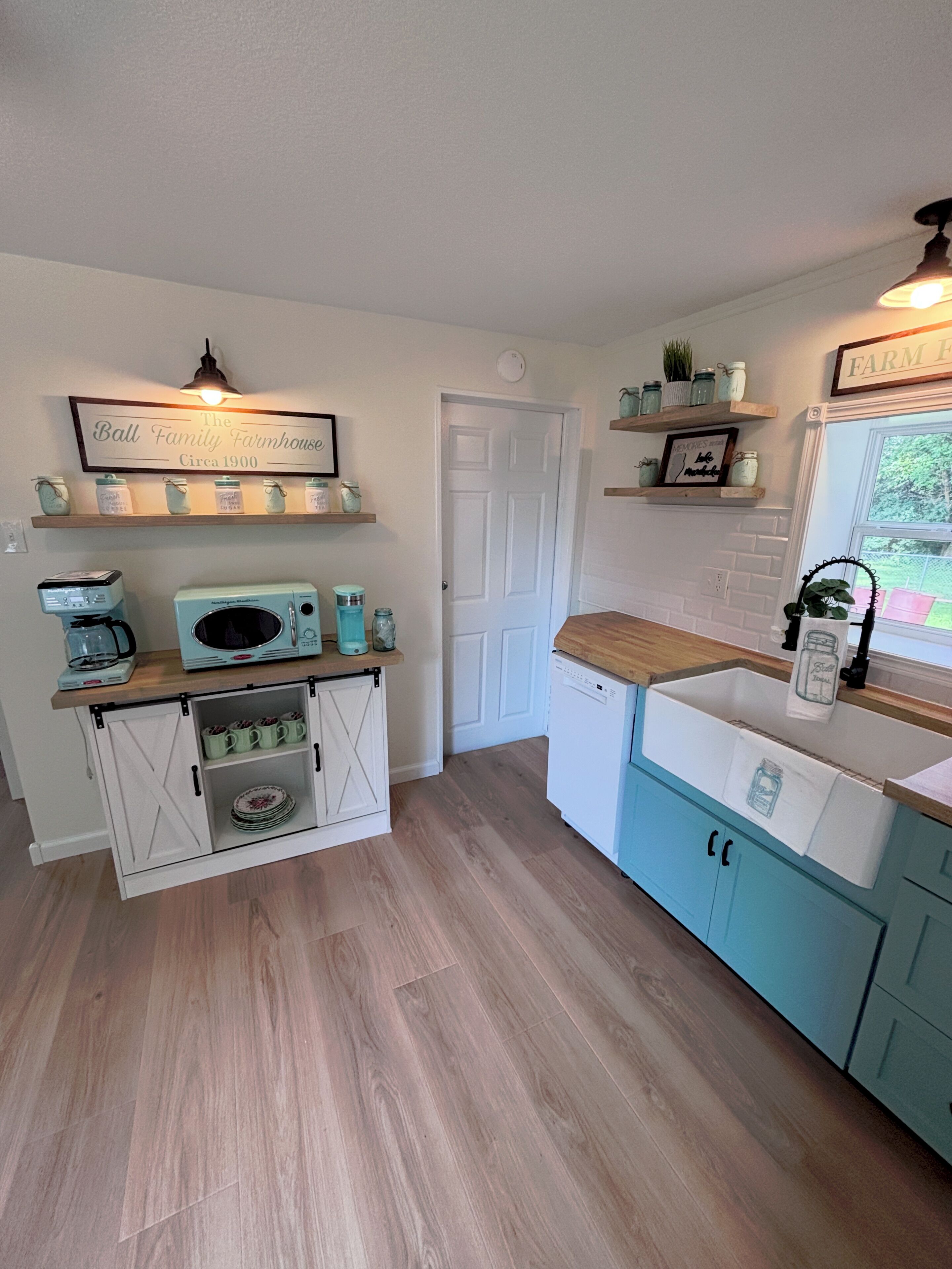 A kitchen with a white door, a coffee maker, a microwave, and a sink.