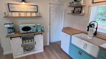 A kitchen with a white door, a coffee maker, a microwave, and a sink.