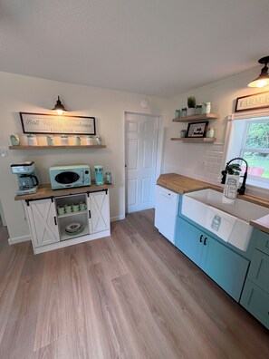 A kitchen with a white door, a coffee maker, a microwave, and a sink.