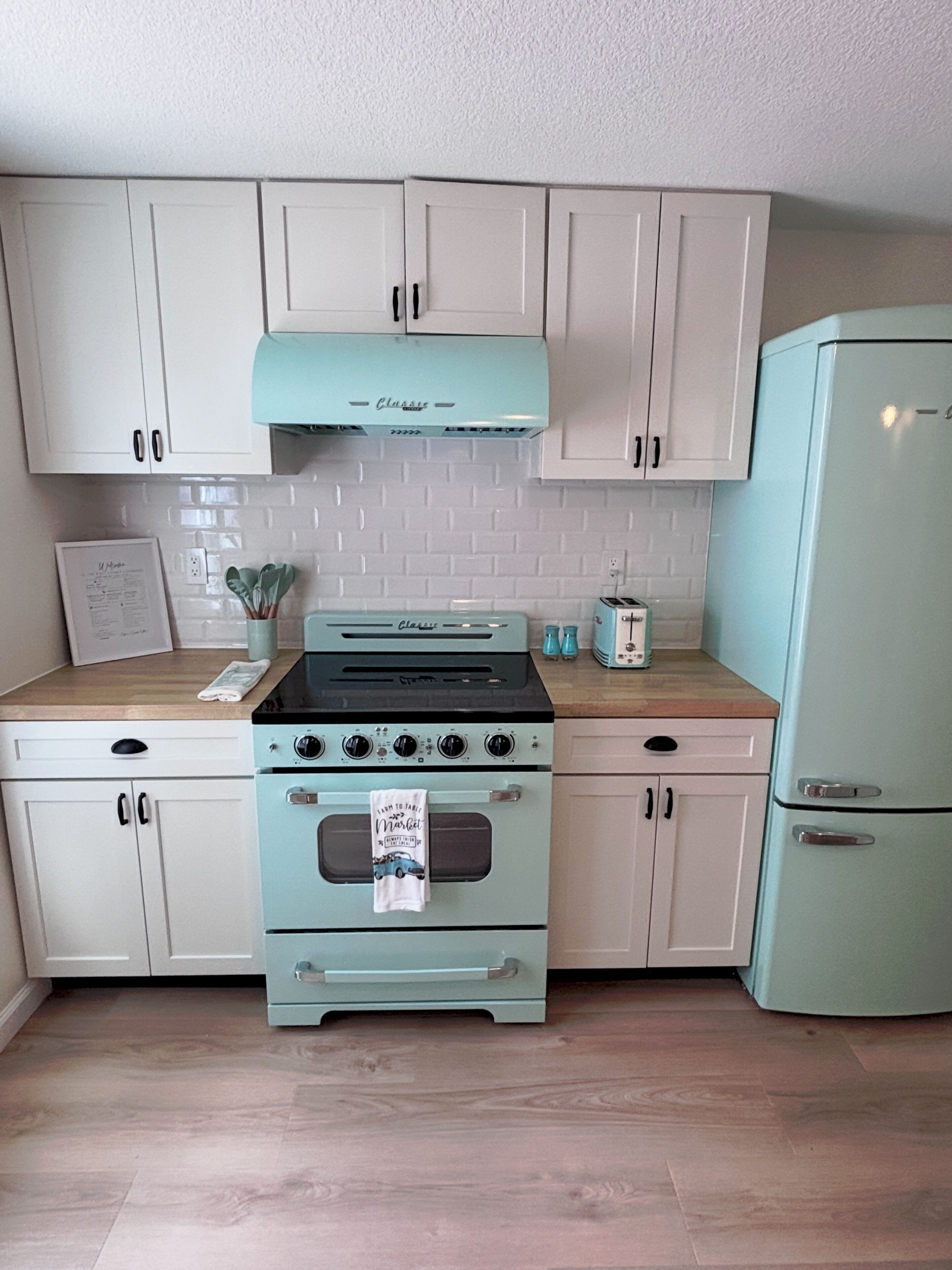 A kitchen with light blue appliances, white cabinets, and a wooden countertop.