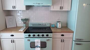 A kitchen with light blue appliances, white cabinets, and a wooden countertop.