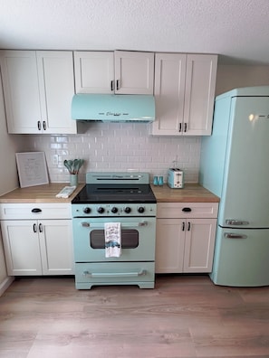 A kitchen with light blue appliances, white cabinets, and a wooden countertop.