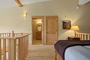 Een slaapkamer met een bed, een nachtkastje, een lamp, een houten deur en een zichtbare badkamer door een open deur.