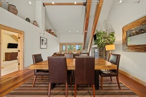 Een eetgedeelte met een houten tafel, lederen stoelen en een gestreept vloerkleed.