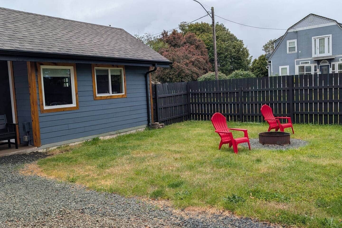 A house with a blue exterior, a wooden deck, and a gravel driveway.