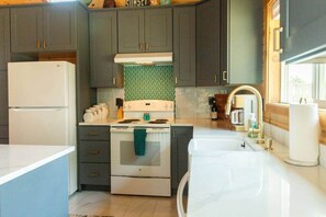 A kitchen with dark cabinets, a white stove, and a sink with gold fixtures.